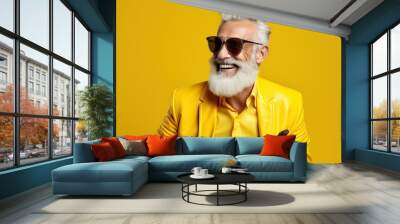 Happy bearded senior man in colorful yellow outfit, cool sunglasses, laughing and having fun in fashion studio Wall mural