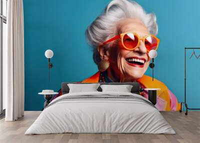 Happy senior woman in colorful neon outfit, funny sunglasses and extravagant style, laughing and smiling, trendy grandma posing in studio Wall mural