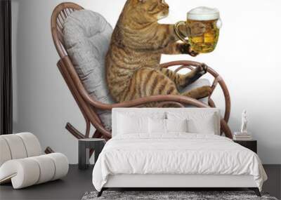 A beige cat in a wooden rocking chair is drinking beer. White background. Isolated. Wall mural