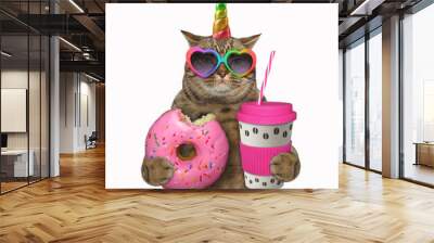 The beige cat unicorn in rainbow heart shaped sunglasses is holding a bitten donut and a pink paper cup of coffee with a plastic lid and a straw. White background. Isolated. Wall mural