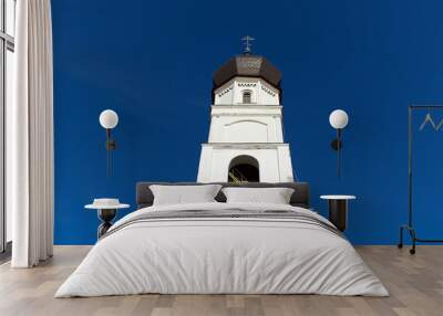 bright white central tower of orthodox cathedral with cross on blue sky background Wall mural