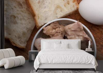 Canned cod liver in a bowl, two pieces of bread and an egg on a wooden board Wall mural