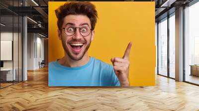 A man with glasses is pointing at something and smiling Wall mural