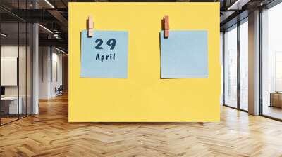 April 29st. Day of 29 month, calendar date. Two blue sheets for writing on a yellow background. Top view, copy space. Spring month, day of the year concept Wall mural