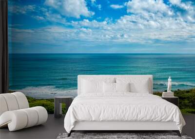 Picturesque ocean landscape with gentle sea waves lapping over quiet beach surrounded by green, beautiful sky with white cloud above. Hokianga, Northland, New Zealand Wall mural