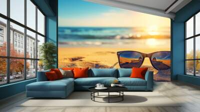 Beach concept - sunglasses on on a sandy beach with sunset light and blue sea background. Wall mural