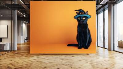 Black British cat in witch hat on orange background. Halloween witch kitten in black pointed hat. Masquerade party. Festive carnival. Concept of spooky decoration, pet costumes. Banner with copy space Wall mural