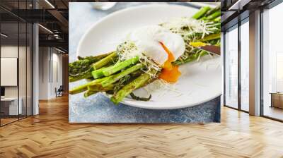 Green asparagus with poached egg and parmesan, vegetarian breakfast served on two white plate on light background. Wall mural