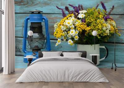 Fresh medicinal herbs in a metal jar and dry medicinal herbs in a bowl on a table together with a kerosene lamp on a wooden old background . Wall mural