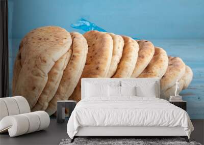 Freshly baked pita bread or flatbread on blue wooden background. Wall mural