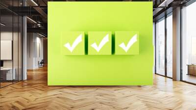 Three white checkmarks on green toy cubes in a row against bright green background. Checklist concept Wall mural