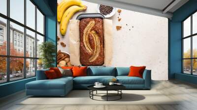 Traditional American homemade banana bread with chopped walnuts, chocolate and cinnamon in loaf pan on light background. Fruit cake. Healthy vegan desserts concept. Top view, copy space. Wall mural