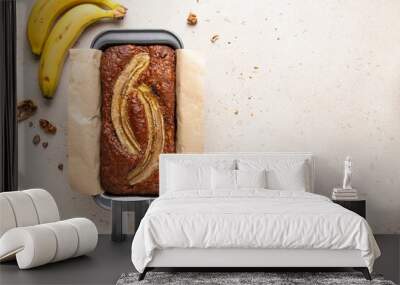 Traditional American homemade banana bread with chopped walnuts, chocolate chips and cinnamon in loaf pan on light background. Fruit cake. Healthy vegan desserts concept. Top view, copy space. Wall mural