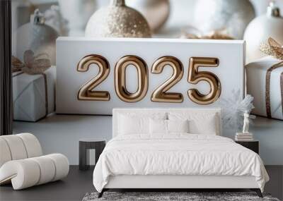 A 3D gold '2025' design surrounded by Christmas ornaments and presents on a white surface Wall mural