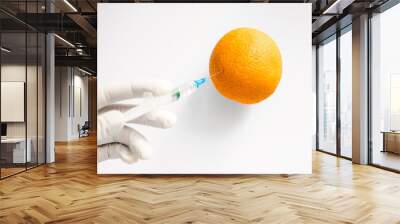 laboratory assistant injects chemicals with a syringe into an orange. fruits are processed for long-term storage. processed edible vegetables and fruits on a white background. genetic engineering layo Wall mural