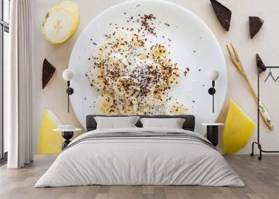 Low calorie dessert. Banana, chocolate and coconut flakes on white plate. Wall mural