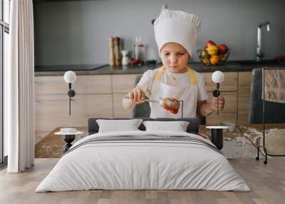 Adorable happy girl in chefs hat and apron cooking pizza at the kitchen Wall mural