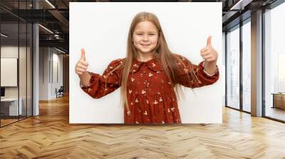 Photo of cheerful happy young small girl make fingers thumbs up smile recommend isolated on green color background Wall mural