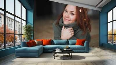 Indoor portrait of young smiling beautiful woman enjoying time at scandinavian style home, sitting on the on the floor in warm green sweater. Golden Christmas confetti on hair. Wall mural