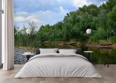 riverbank with gravel and calm water and green trees before rain copy space Wall mural