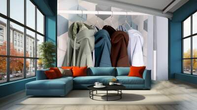 Row of multi-colored knitted hoodies, sports sweaters hanging on a hangers in an atelier or sportswear of Retail store close-up. pastel cold colors Wall mural