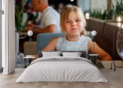 Adorable little girl having breakfast at resort restaurant. Happy preschool child eating healthy food, vegetables and eggs in the morning. Wall mural