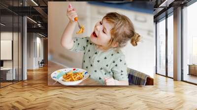 Adorable toddler girl eat pasta macaroni bolognese with minced meat. Happy child eating fresh cooked healthy meal with noodles and vegetables at home, indoors. Wall mural