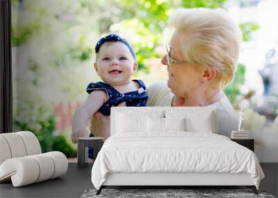 Cute little baby girl with grandmother on summer day in garden Wall mural