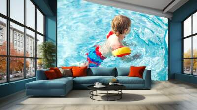 Happy little kid boy having fun in an swimming pool. Active happy child learning to swim. with safe floaties or swimmies. Family, vacations, summer concept Wall mural