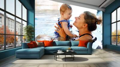 Happy mother swimming with cute adorable baby girl daughter in swimming pool spending spa vacations Wall mural