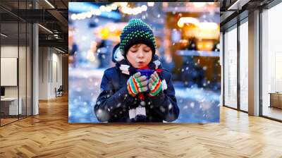 Little cute kid boy drinking hot children punch or chocolate on German Christmas market. Happy child on traditional family market in Germany, Laughing boy in colorful winter clothes Wall mural