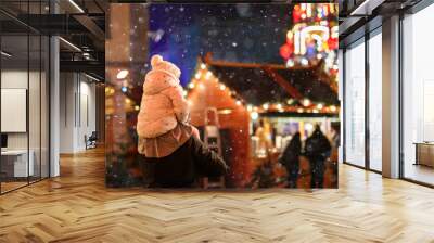 Little preschool girl sitting on shoulder of father on Christmas market in Germany. Happy toddler child and man observing traditional decorated pyramid. Happy family, bonding, love. Family xmas time. Wall mural