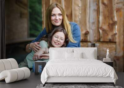 Portrait of little school girl with glasses and mother hugging together. Cute daughter and happy woman. family, childhood, happiness and people Wall mural