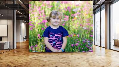 Portriat of adorable, charming toddler girl in flowers meadow. Smiling happy baby child on summer day with colorful flowers, outdoors. Happiness and summertime. Wall mural