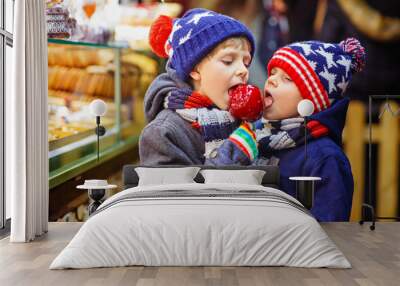 two little kid boys eating sugar apple sweets stand on christmas market Wall mural