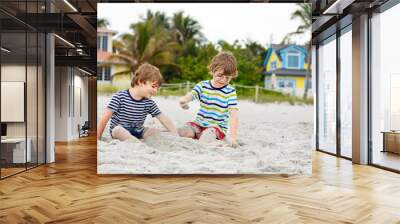 Two little kids boys having fun on tropical beach, happy best friends playing, friendship concept. Siblings brothers, twins in family look with palms on background. Family vacations on Florida. Wall mural