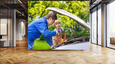 young father teaching his little son to change motor oil in fami Wall mural