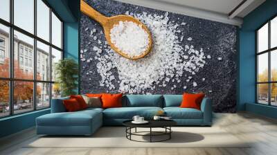 Sea salt in a wooden spoon on a black background Wall mural