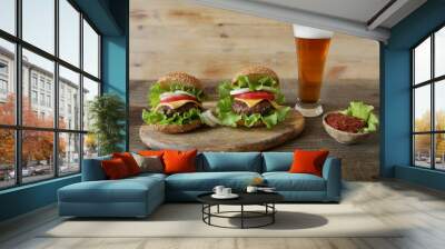 Two perfect hamburger with beef patty, with cheese, pickles, tomatoes, onions, lettuce and tomato sauce in a saucer with a glass of beer on a wooden rustic background with copy space for text. Wall mural