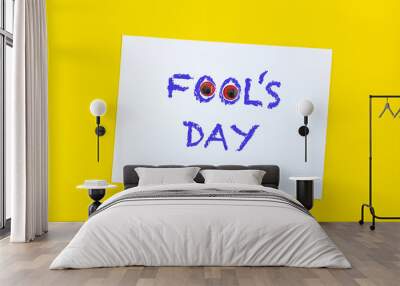 Text word Fool's day on sheet of paper with funny eyes and. 1 april message handwritting on sheet of paper. Bright yellow background. International humor day Wall mural