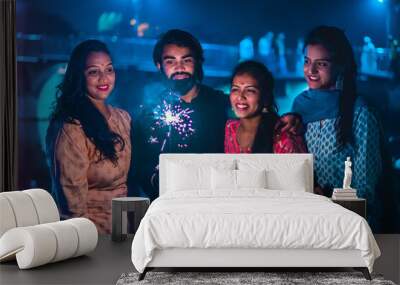 Three young Indian women and a men with bengal fireworks, celebrating. Indian Festival Diwali. New Year Celebrations. 
 Wall mural