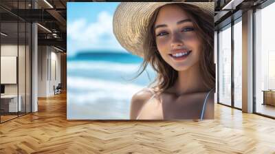 A cheerful young woman smiles brightly at the beach. She wears a stylish straw hat and a simple swimsuit. The sun is shining and the ocean waves are gentle.  Wall mural