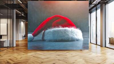 A vibrant red Christmas hat rests on a textured surface. This image captures the festive spirit of the holiday season. Perfect for seasonal promotions and decorations. AI Wall mural