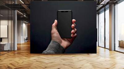 close-up of a hand holding a modern smartphone, isolated on dark background. clear screen for mockup Wall mural