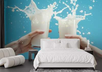 Two hands holding clear glasses filled with refreshing milk. The image captures a playful splash of milk on a vibrant blue background. Perfect for food and beverage promotion. AI Wall mural