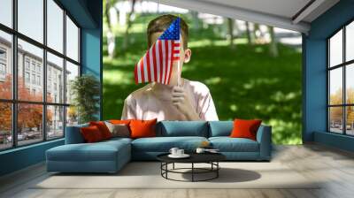 Young boy staying and taking American Flag in hand. Independence Day of USA. Fourth of july Wall mural