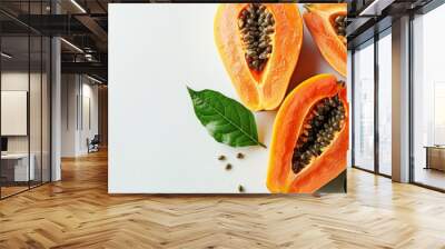 Halved papaya with seeds on white surface. Fresh papaya fruit with vibrant green leaves. Nutritious tropical fruit for a healthy lifestyle. Wall mural