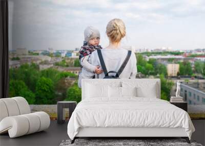 Portrait of young mother and daughter travellers, standing on city roof. Rear view Wall mural