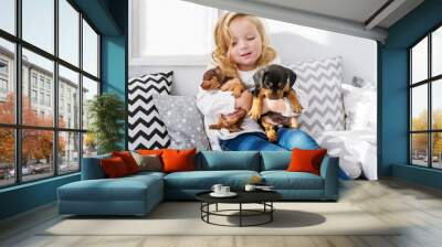 The beautiful little girl embraces two little charming puppies of a dachshund Wall mural