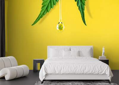 Cannabis leaf and a dropper with drop of CBD OIL close-up on yellow background. Macro. Minimal concept Wall mural